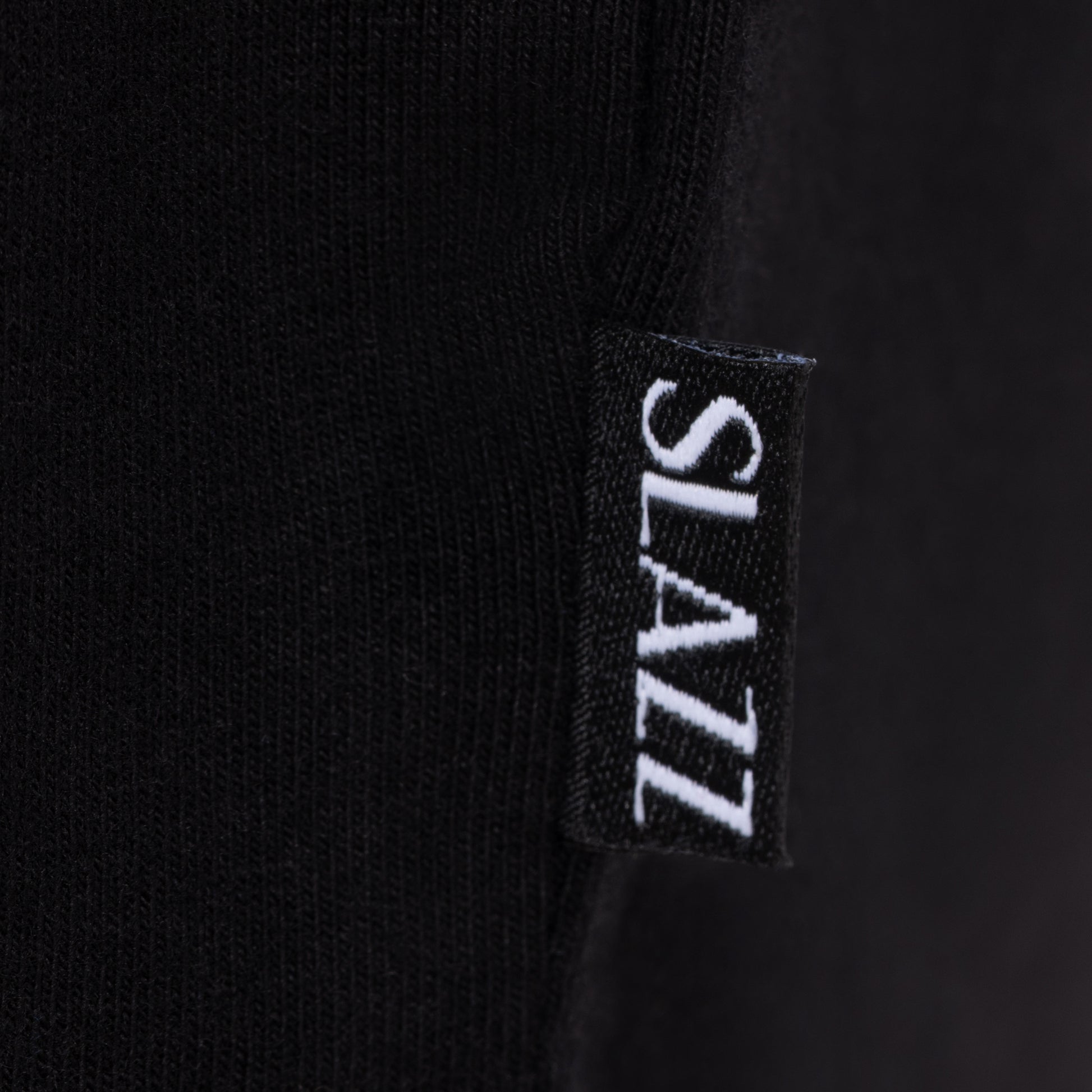 Détail de l'étiquette tissée SLAZZ cousue sur le côté du haut de pyjama noir