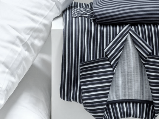 Pyjama homme premium à rayures soigneusement plié sur une table de chevet blanche