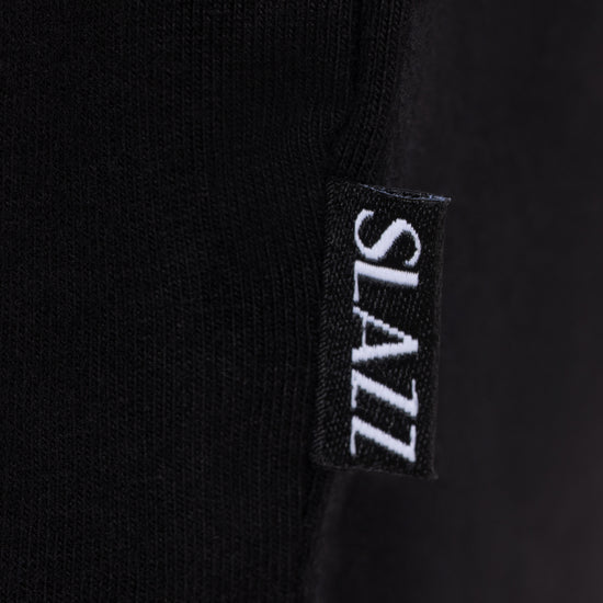 Détail de l'étiquette tissée SLAZZ cousue sur le côté du haut de pyjama noir